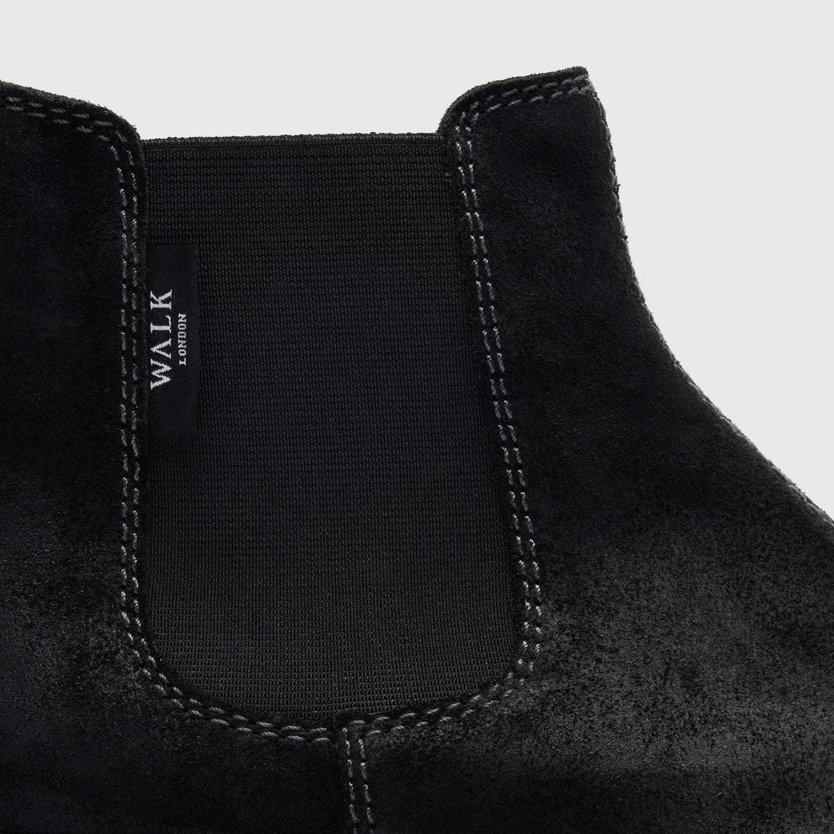 Walk London Clapham Chelsea Boots in black suede close up view showing elastic side panel, branded tab, and stitching detail