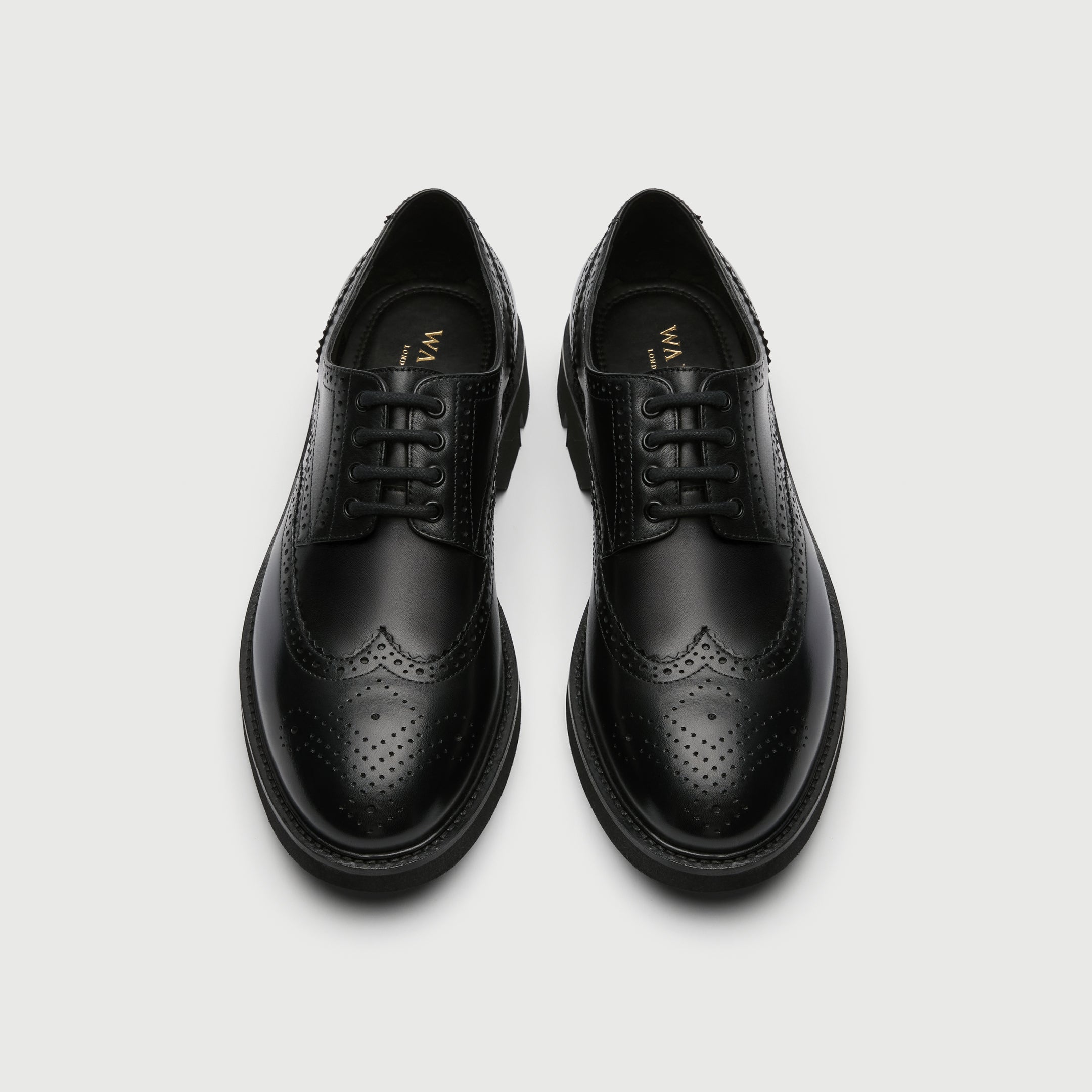 Black leather Walk London Felix brogue shoe on a light grey background - birds eye view