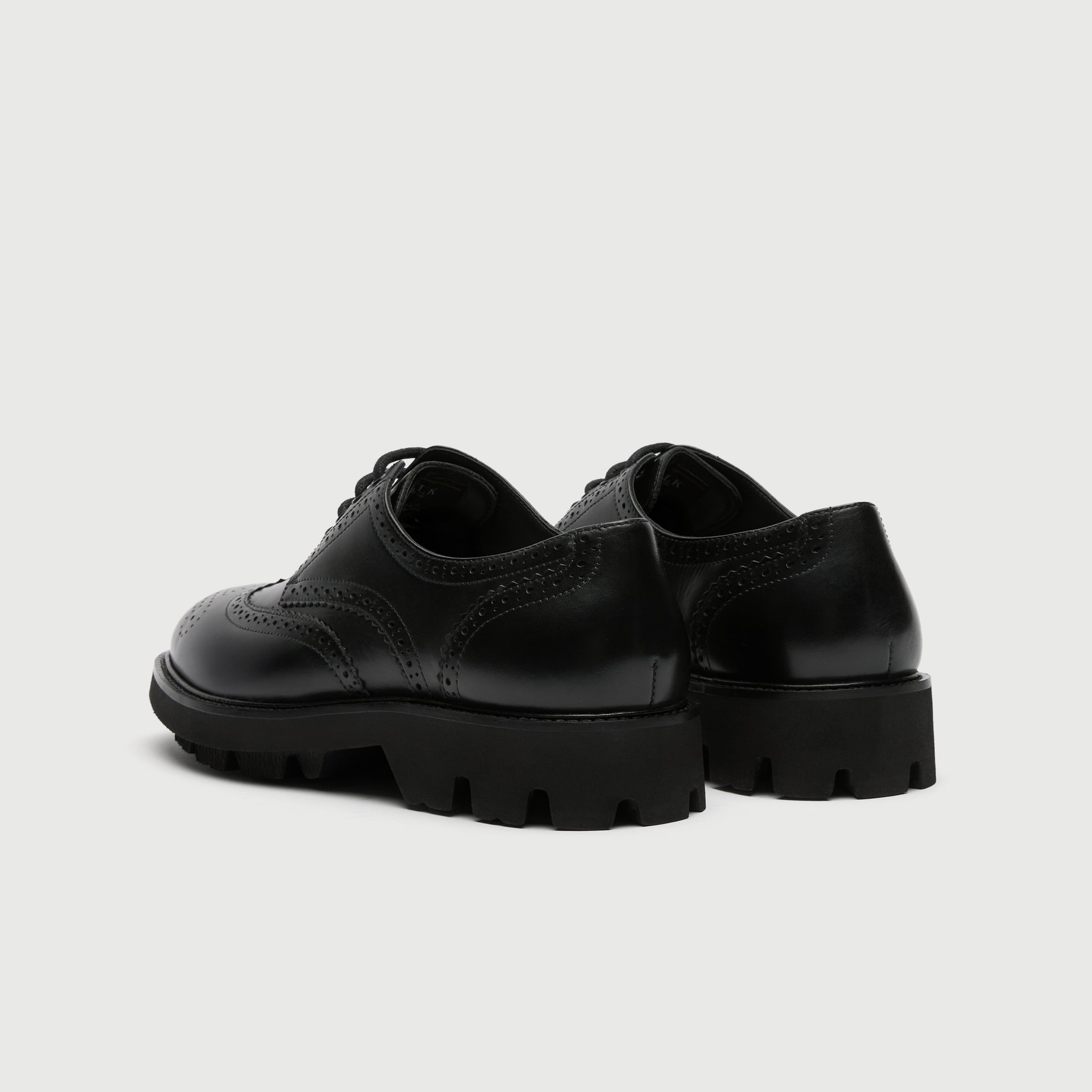 Black leather Walk London Felix brogue shoe on a light grey background - Back view.