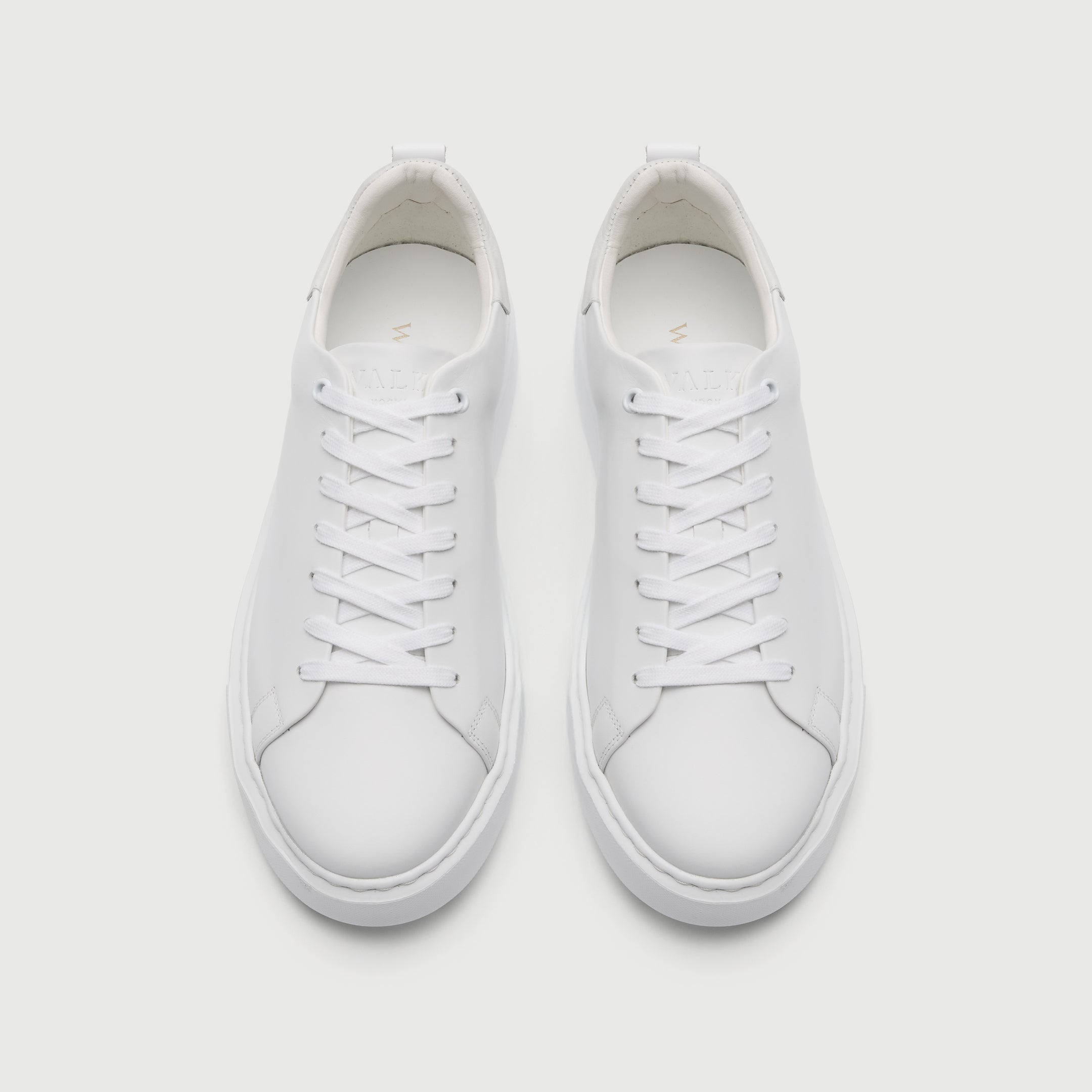 Pair of white sneakers on a light gray background - Walk London Pasadena Trainer in White Leather Top