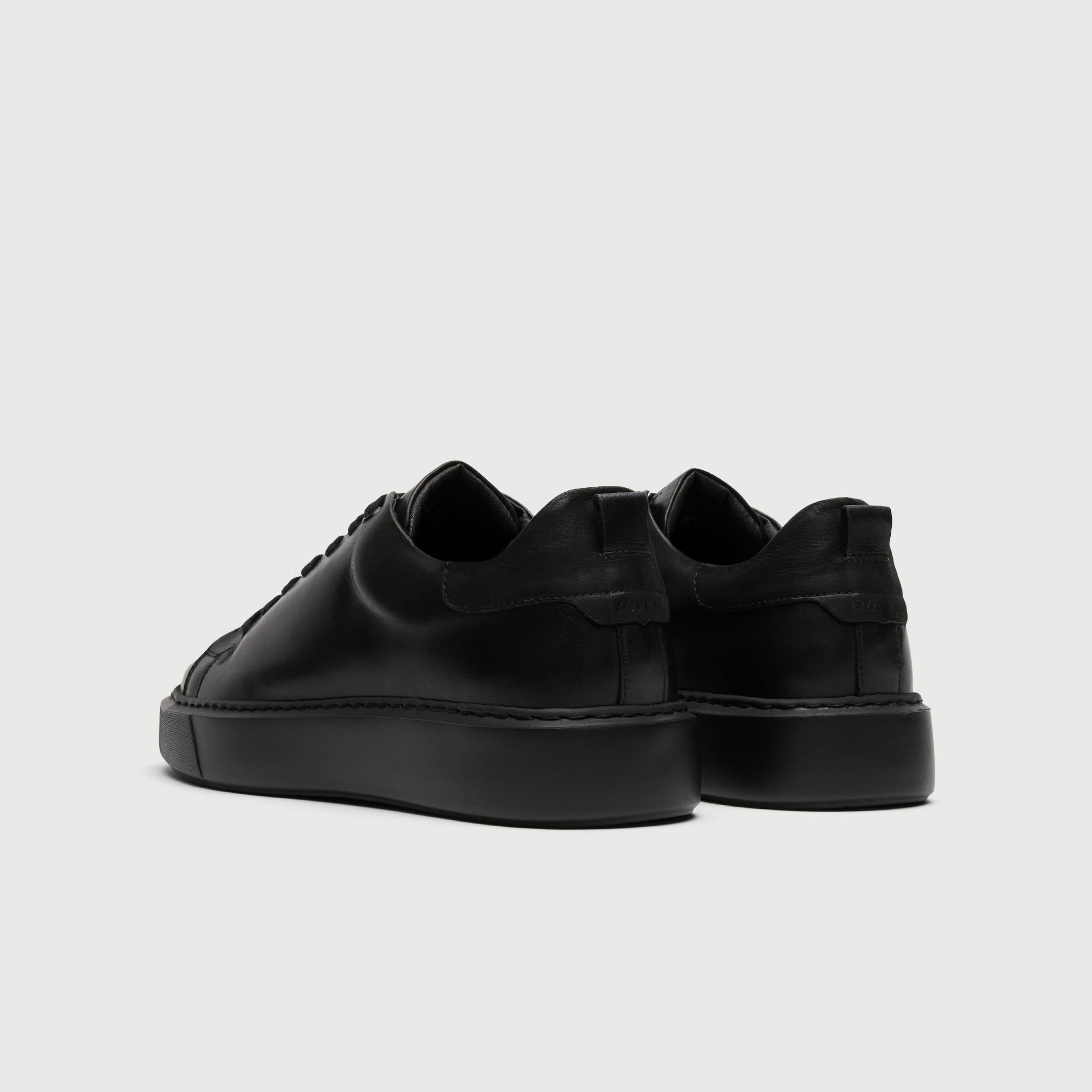 Black sneakers on a light gray background - Walk London Pasadena Trainer in Black Leather