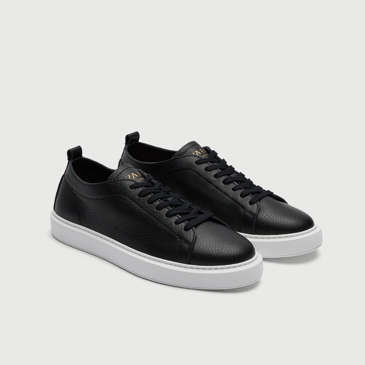 Walk London Wimbledon Trainer in Black Grain Leather three quarter view showing gold foil branding on tongue and seven eyelet fastening with black laces