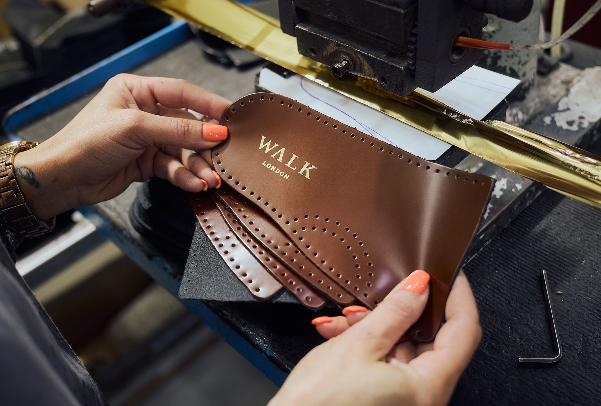 Lady in factory holding brown leather inner sock for a shoe