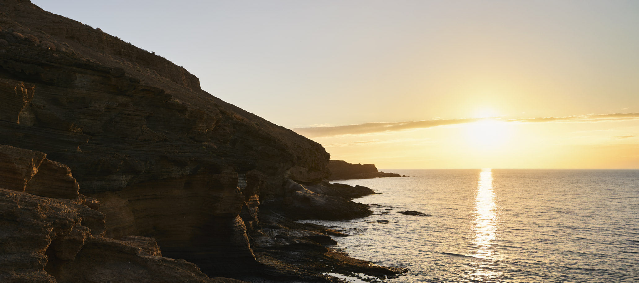 Scenic coastal landscape with sun setting over the sea  