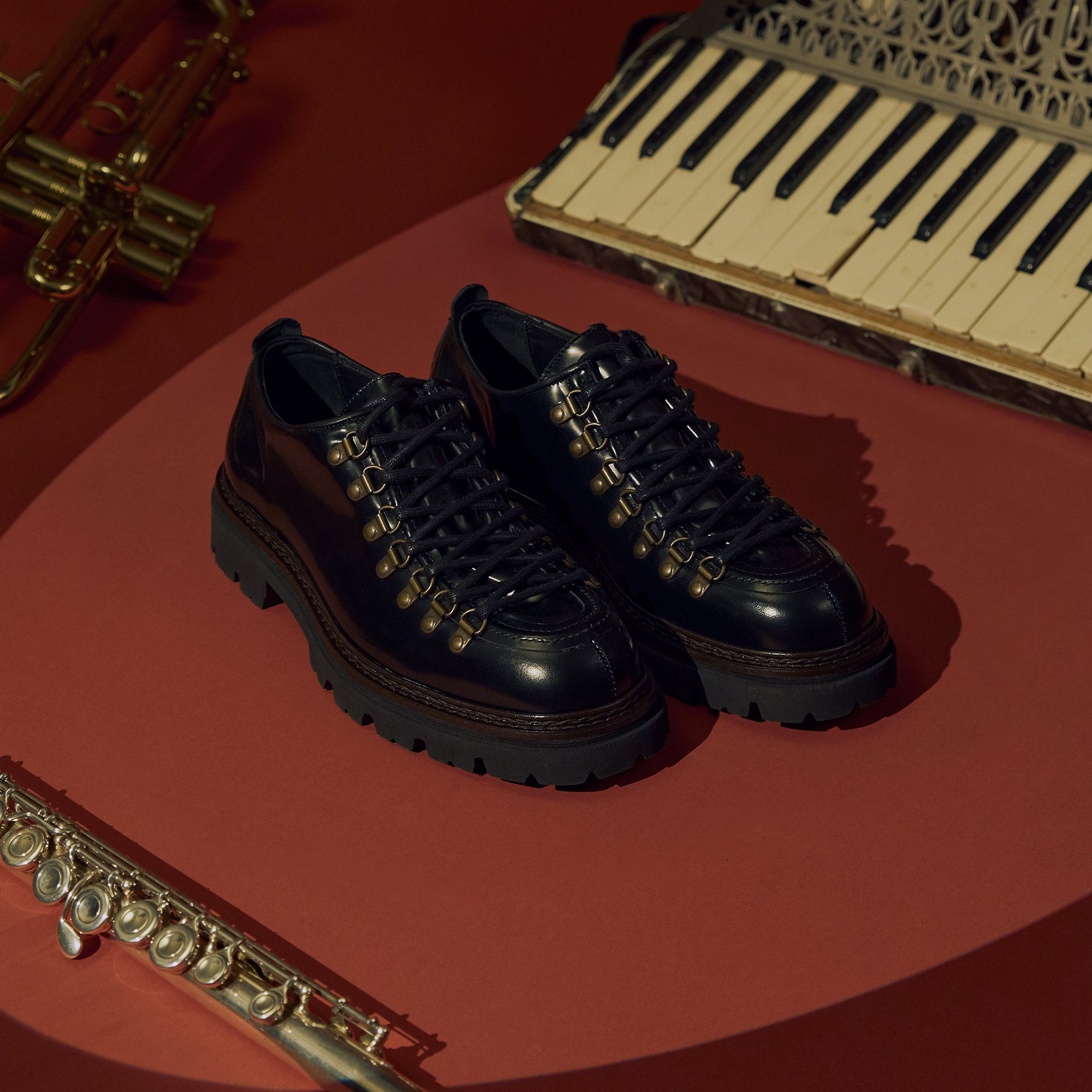 Mens black leather hiking shoes on red background with instruments