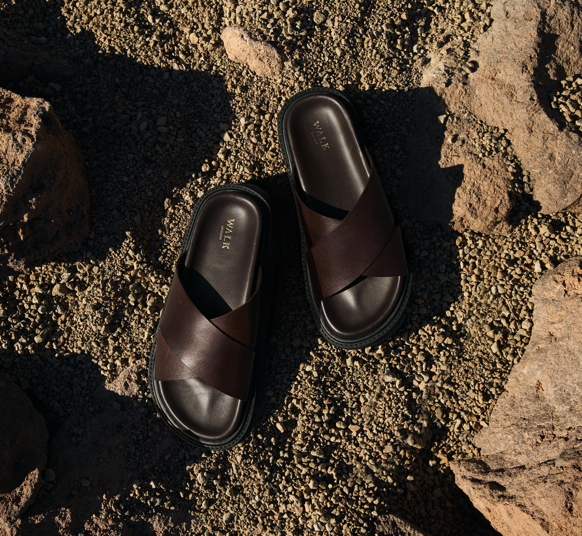 Ezra Cross Strap dark brown leather mens sandals on volcanic rock and gravel