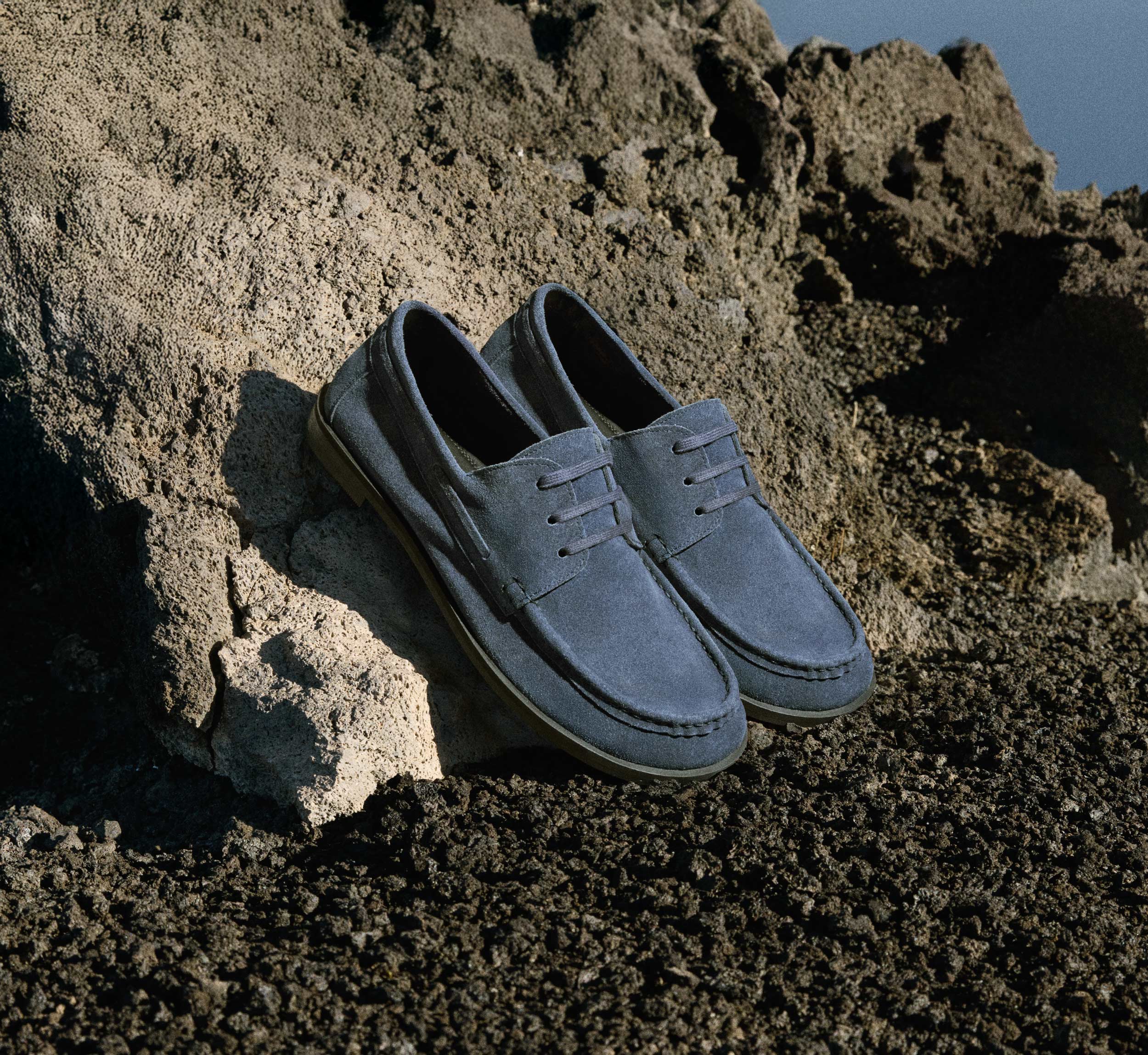 Walk London Roma blue suede boat shoes on rocky background