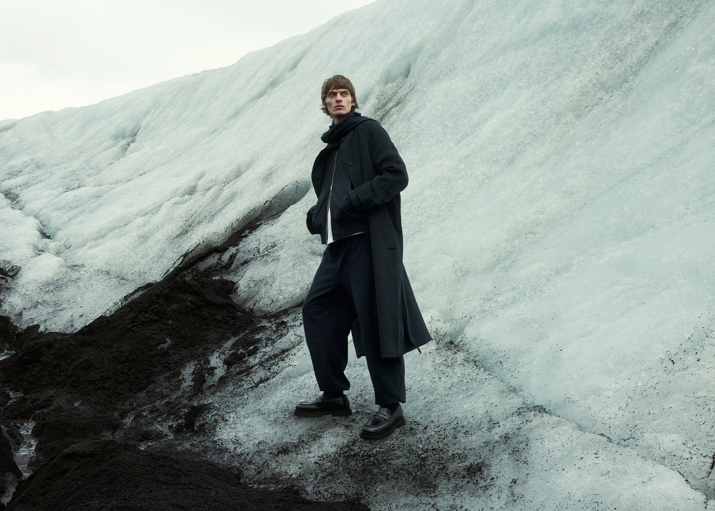 man wearing black leather loafers stood on glacier