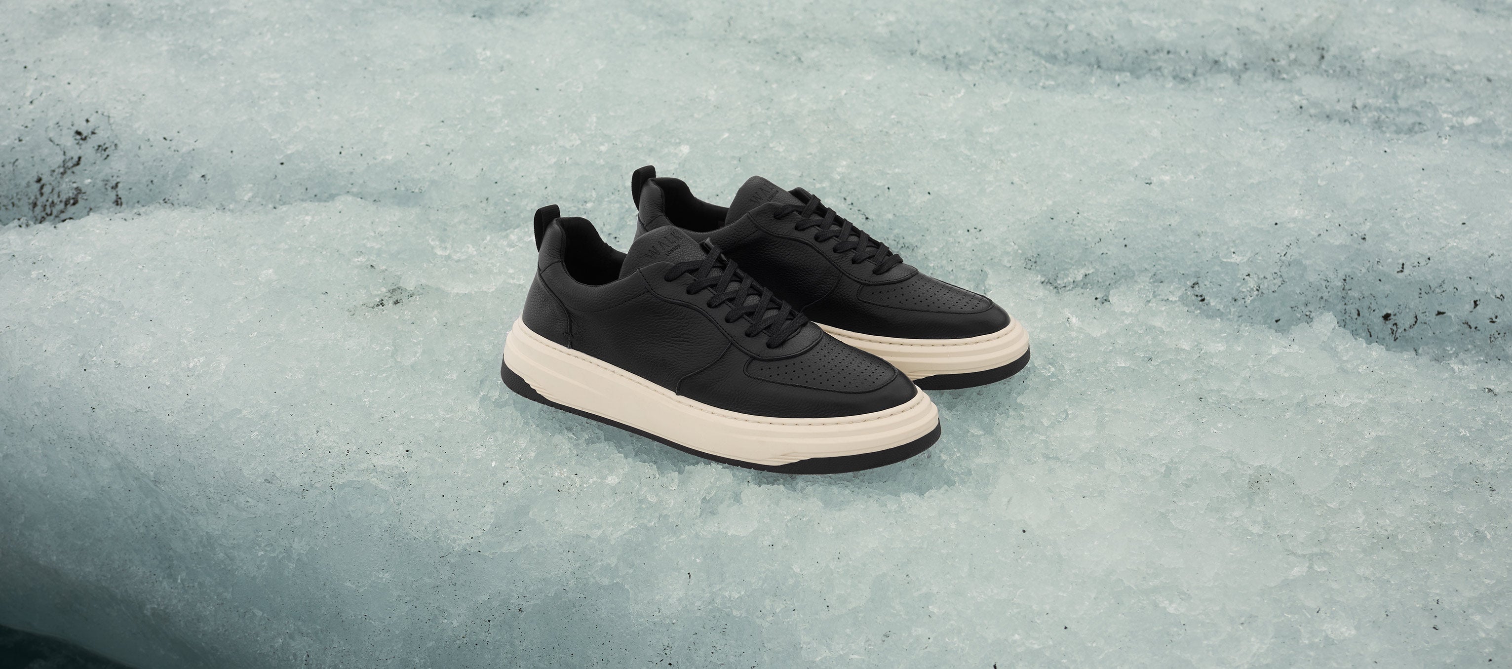 black and white leather trainers on a glacier