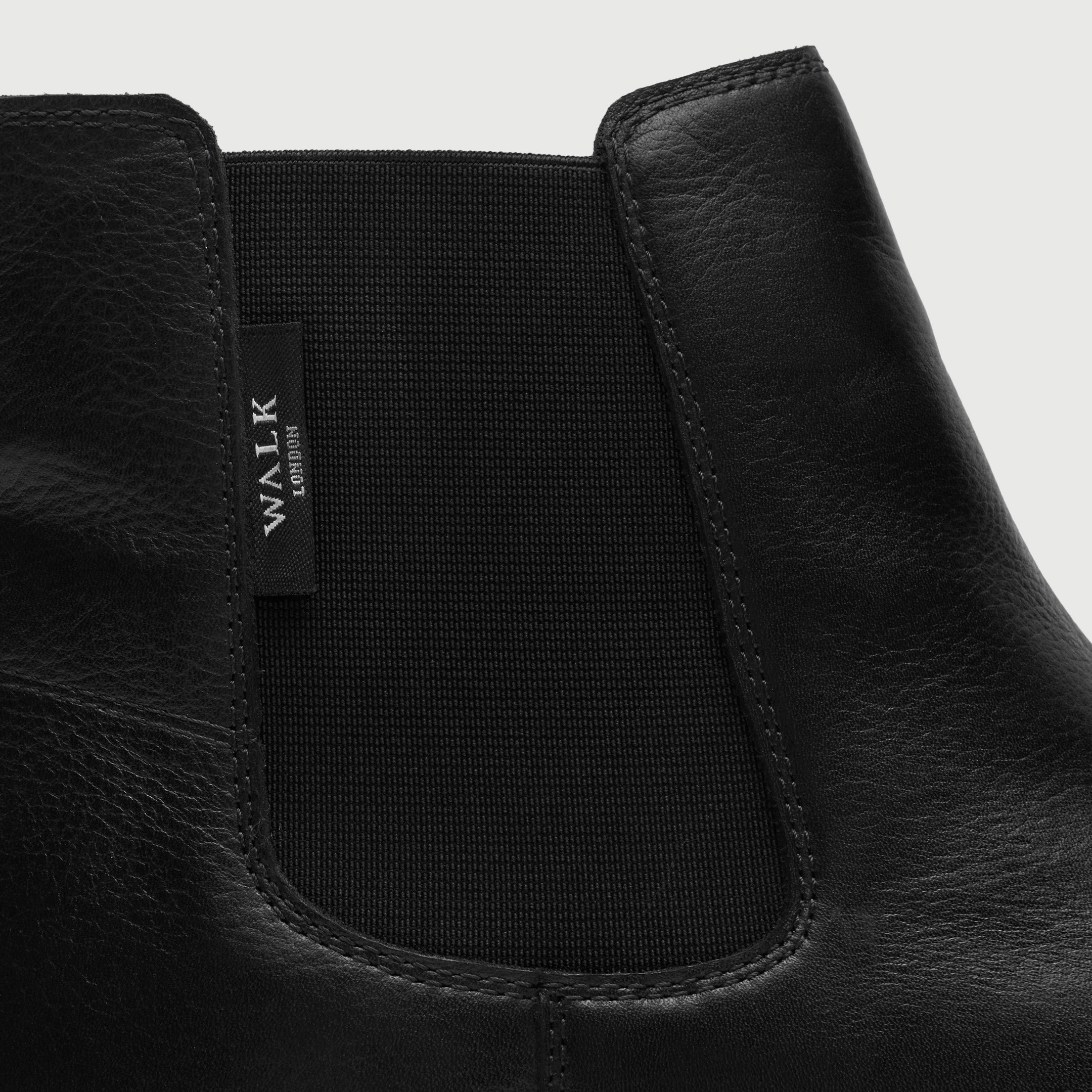 Walk London Hackney Chelsea Boot in Black Leather close up view of the elastic panel and branded label