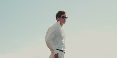 Video of man in summer outfits walking along coastal landscape wearing loafers and sandals