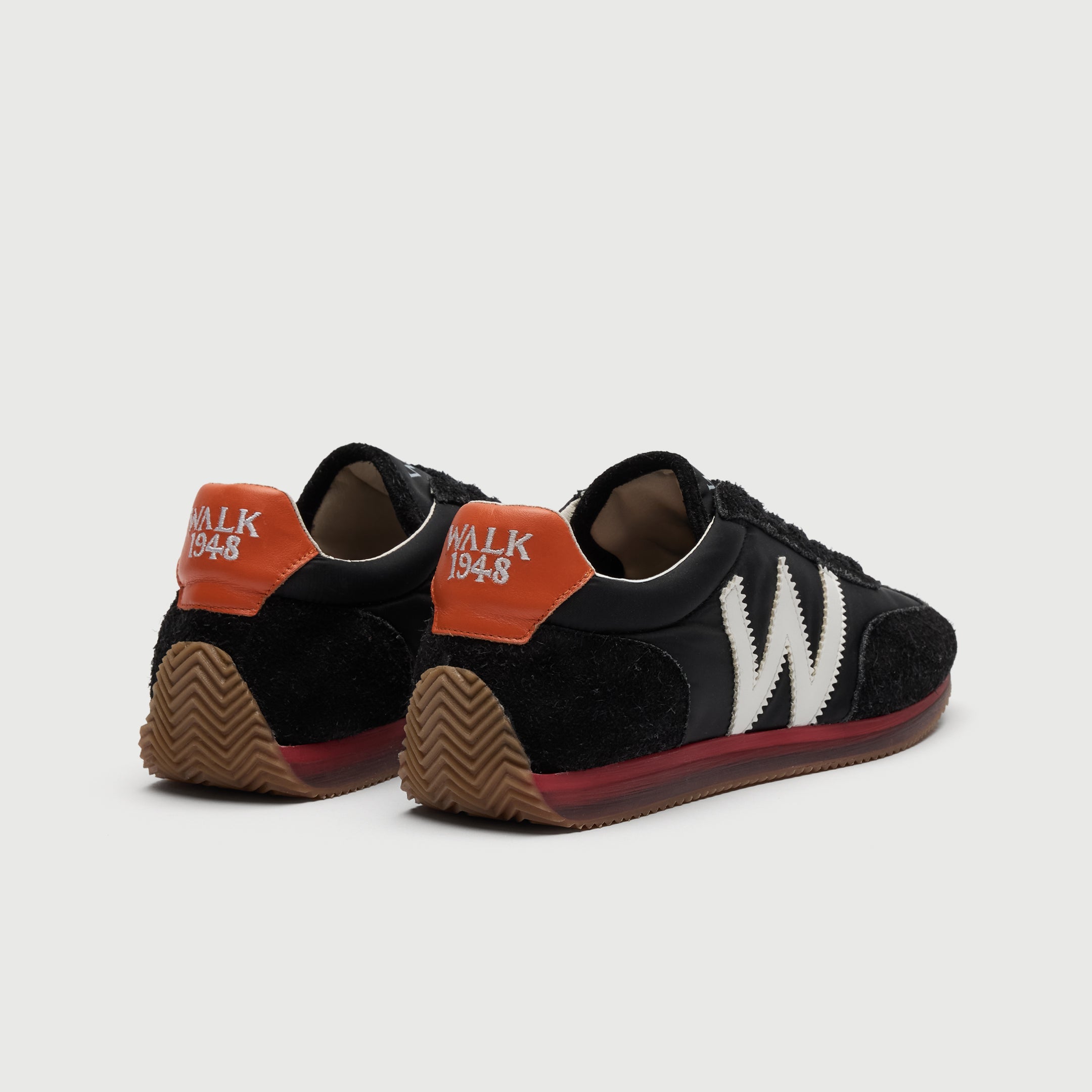 Walk London Retro Runner Trainers in Black Brushed Suede and Textile heel view showing tan ridged sole that extends into heel guard, red and translucent midsole, embroidered WALK 1948 on orange heel counter